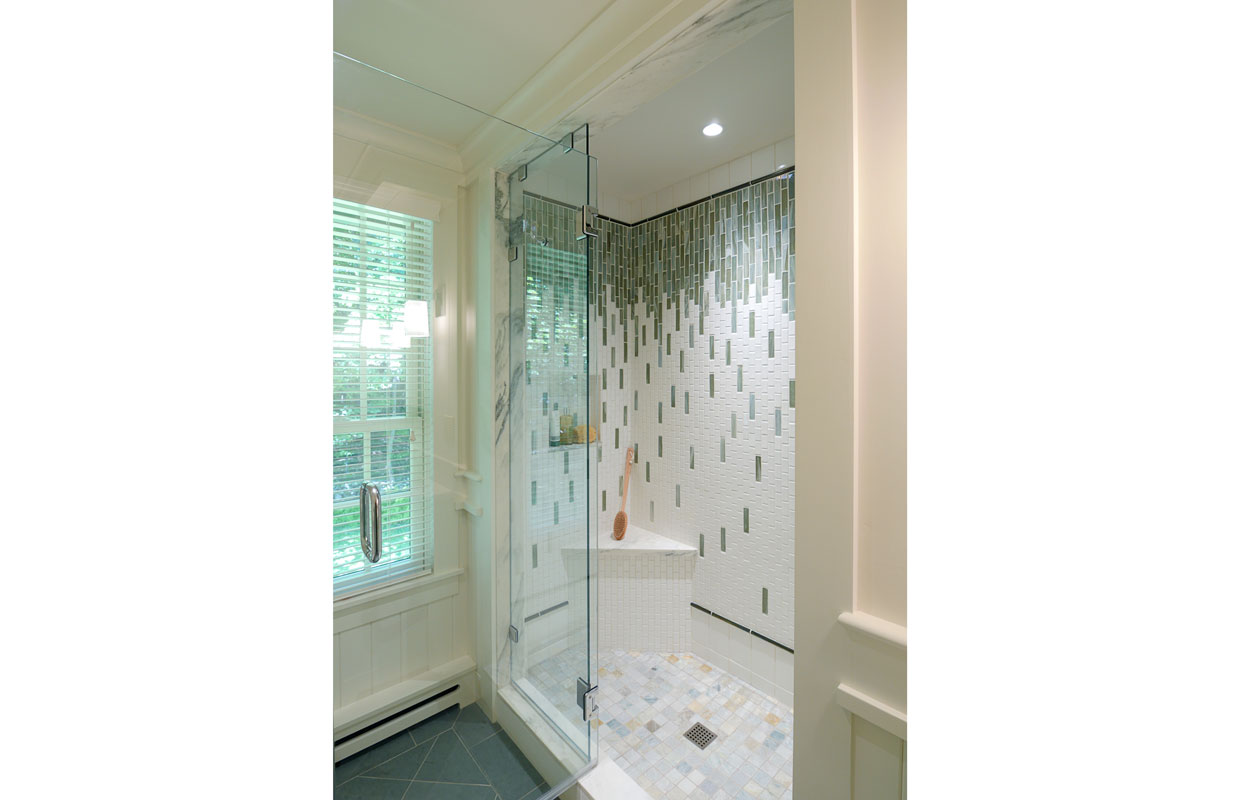 big open tiled shower with a glass wall
