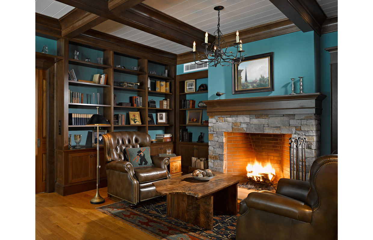 library in a home with a stone fireplace and dark wood accents and aqua paint