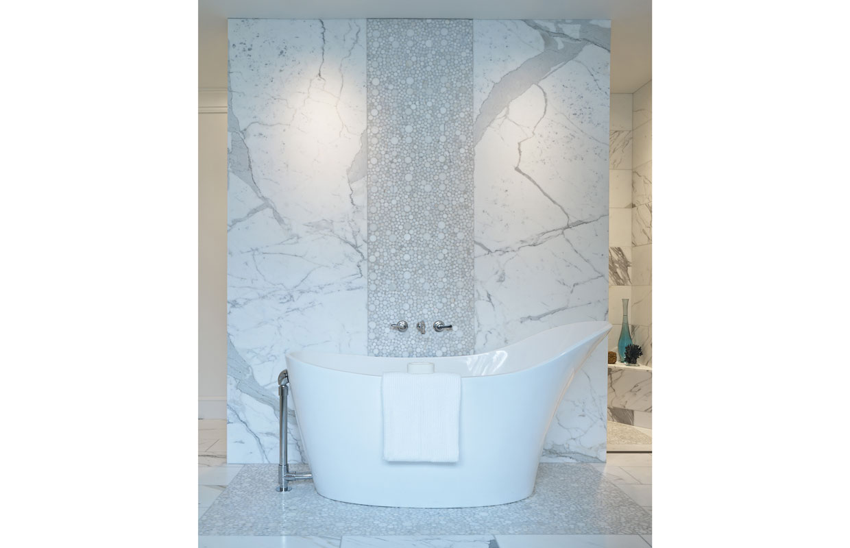 large white modern style bathtub with a marble finish wall